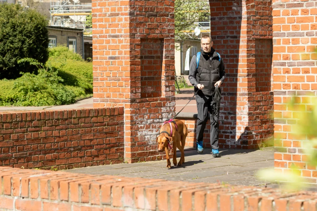 Mann mit Hund unter einem Backsteinbogen.