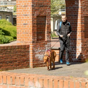 Mann mit Hund unter einem Backsteinbogen.
