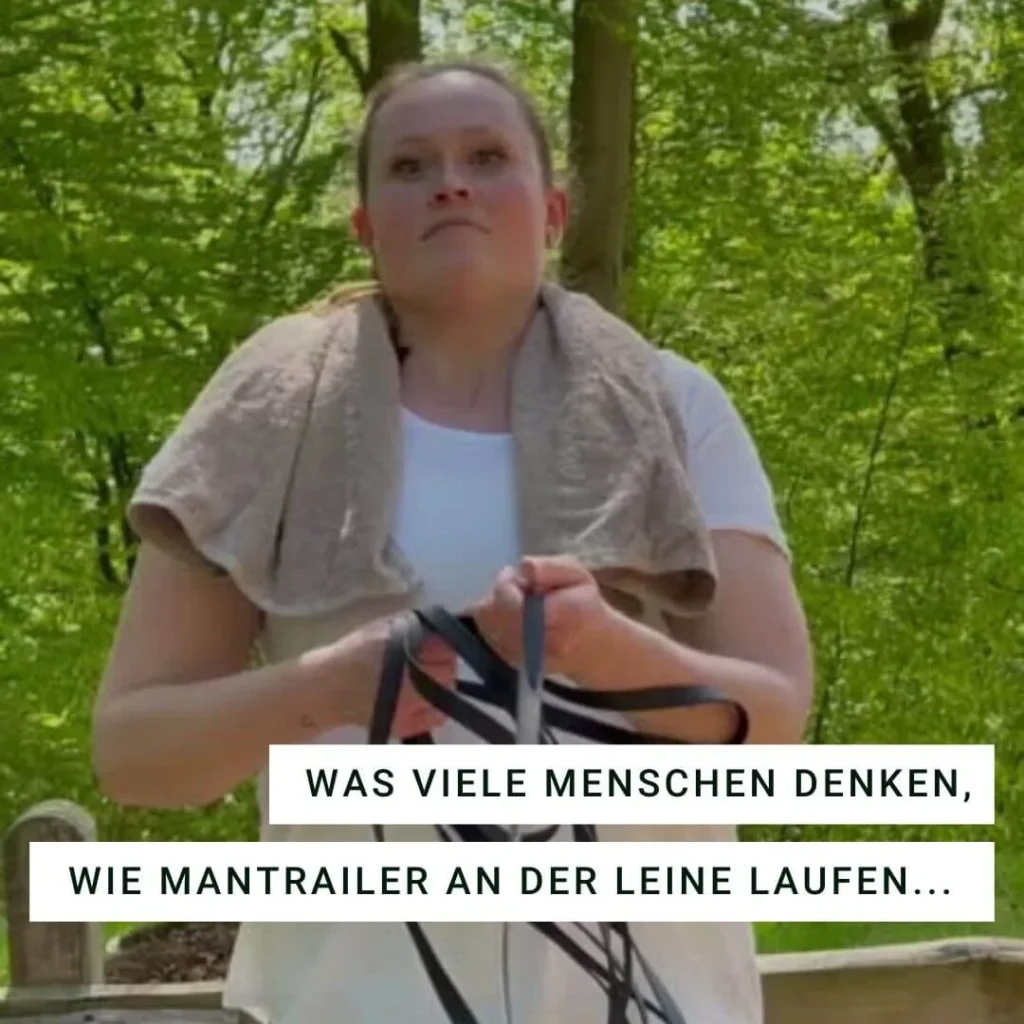 Frau im Wald hält schwarze Leinen in der Hand.