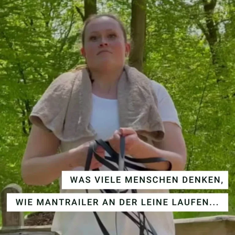 Frau im Wald hält schwarze Leinen in der Hand.