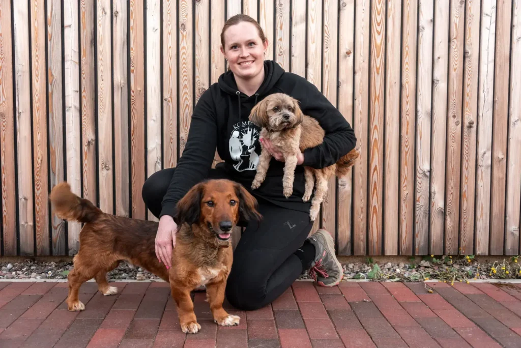Frau mit zwei Hunden in einem Garten.
